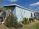 Side view of a light blue single wide manufactured home with landscaping and AC unit at 6432 Keena Ct, North Port, FL 34287