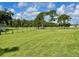 Open pasture with trees and a partially visible home in background at 2573 Chynn Ave, North Port, FL 34286