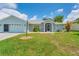 Single story home with light blue exterior, two-car garage, and landscaped lawn at 64 Long Meadow Ln, Rotonda West, FL 33947