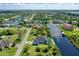 Aerial view showcasing waterfront home with private dock, screened lanai with pool, and lush surroundings at 10454 Atenia St, Port Charlotte, FL 33981