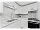 Clean kitchen with sleek white cabinets, gray backsplash, and stainless-steel appliances at 470 S Mccall Rd # 10, Englewood, FL 34223