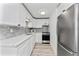 Modern kitchen with sleek white cabinets, gray backsplash, and stainless-steel appliances at 470 S Mccall Rd # 10, Englewood, FL 34223