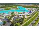 Wide aerial view of a community lagoon featuring waterpark, beach, restaurant, and surrounding neighborhoods at 7537 Pool Compass Loop, Wesley Chapel, FL 33545