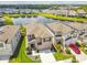Aerial view of home, neighborhood, and lake, with landscaped lawns and waterfront community amenities at 7537 Pool Compass Loop, Wesley Chapel, FL 33545