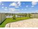 Landscaped backyard features a paver patio, lush lawn, black metal fence, and a serene pond view at 7537 Pool Compass Loop, Wesley Chapel, FL 33545