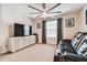 Carpeted bedroom with a ceiling fan, TV, and a window with blinds and curtains at 7537 Pool Compass Loop, Wesley Chapel, FL 33545
