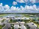 Aerial view of the community amenities, including a lake, clubhouse, and tennis courts at 9982 Beachwalk Dr, Englewood, FL 34223