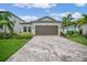 Single-story home with a brown garage door, landscaping, and a brick paver driveway at 1352 Sunset Preserve Way, Port Charlotte, FL 33953