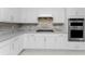 Modern kitchen with white cabinets, stainless steel appliances, and gray countertops at 9982 Beachwalk Dr, Englewood, FL 34223