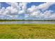 Serene lakefront view with grassy area and distant homes visible at 14589 Ponce De Leon Trl, Port Charlotte, FL 33981
