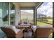 Relaxing screened patio with wicker furniture, overlooking a lush green backyard at 14589 Ponce De Leon Trl, Port Charlotte, FL 33981