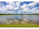 Peaceful lakefront view with calm water and lush green grass at 14589 Ponce De Leon Trl, Port Charlotte, FL 33981