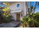 This home features a unique, arched wood door with a quaint awning and decorative palms in the landscaping at 11000 Placida Rd # 2303, Placida, FL 33946