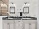 Elegant bathroom featuring double sinks, black marble countertop, decorative mirrors and vanity with storage at 11160 Hacienda Del Mar Blvd # D-205, Placida, FL 33946