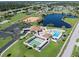 Aerial view of community amenities featuring a pool, clubhouse, and green space by a pond at 6367 Facet Ln, Port Charlotte, FL 33981