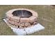 Brick fire pit situated on a grass lawn and surrounded by white stone pavers at 6367 Facet Ln, Port Charlotte, FL 33981