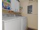 Functional laundry area featuring a washer, dryer, cabinet storage, and a wall-mounted electrical panel at 6367 Facet Ln, Port Charlotte, FL 33981