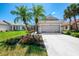 Charming home features a well-manicured lawn, colorful flowerbeds, and tall palm trees, creating curb appeal at 3359 Osprey Ln, Port Charlotte, FL 33953