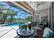 Covered lanai with comfortable seating overlooks a sparkling pool and lush landscaping, offering a relaxing outdoor space at 3359 Osprey Ln, Port Charlotte, FL 33953