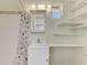 A bathroom with white vanity, mirror and open shelving, with a shower and patterned curtain at 797 Michigan Ave, Englewood, FL 34223