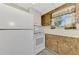 A kitchen featuring white appliances, wood cabinets, and a window with floral curtains at 797 Michigan Ave, Englewood, FL 34223
