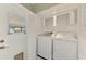Bright laundry room with washer, dryer, overhead storage, and natural light at 797 Michigan Ave, Englewood, FL 34223
