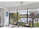 Bright lanai with lake view, wicker furniture, and window shades at 504 Pine Hollow Cir # 504, Englewood, FL 34223