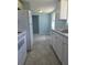 White cabinets and appliances in a galley-style kitchen with grey flooring at 317 E Green St, Englewood, FL 34223