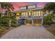 Two-story home with a metal roof, large windows, and a brick driveway at 22 Seawatch Dr, Boca Grande, FL 33921