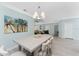 Open dining area with large palm tree art and modern light fixture, open to living spaces at 552 Box Elder Ct, Englewood, FL 34223