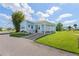 Charming manufactured home with a covered porch, light blue exterior, and well-manicured lawn at 5704 Holiday Park Blvd, North Port, FL 34287