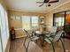 Cozy sun room has four chairs and a table on an area rug with sliding glass door leading to the backyard at 5704 Holiday Park Blvd, North Port, FL 34287