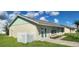 Tan house with green accents, a spacious yard, and a white fence at 13528 Martha Ave, Port Charlotte, FL 33981