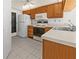 Galley kitchen with wood cabinets, and white appliances at 404 Cypress Forest Dr, Englewood, FL 34223