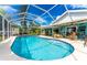 Inviting kidney-shaped pool with a screened enclosure and patio furniture at 13511 Foresman Blvd, Port Charlotte, FL 33981
