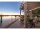 Waterfront home with a covered patio, wood chairs, and a private dock for enjoying the sunset at 15172 Leipzig Cir, Port Charlotte, FL 33981