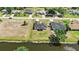 The aerial view shows a neighborhood with a water feature behind a home featuring a dark roof and green lawn at 220 Mark Twain Ln, Rotonda West, FL 33947