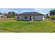 The backyard features a covered porch, a lawn area, and minimalistic landscaping, ideal for relaxation and entertaining at 220 Mark Twain Ln, Rotonda West, FL 33947