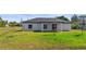 The backyard offers a serene view of the home's exterior, framed by a lush lawn, complemented by modern windows at 220 Mark Twain Ln, Rotonda West, FL 33947
