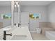 Bright bathroom featuring double vanity, soaking tub, and a window offering a scenic view at 220 Mark Twain Ln, Rotonda West, FL 33947