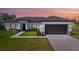Charming home with black garage door, and manicured lawn and landscaping at dusk at 220 Mark Twain Ln, Rotonda West, FL 33947