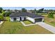 Inviting single-story home with an attached garage, manicured lawn, and a sleek gray roof at 220 Mark Twain Ln, Rotonda West, FL 33947