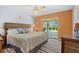 Bedroom with orange accent wall, ceiling fan, and access to the lanai and pool area at 61 Pinehurst Pl, Rotonda West, FL 33947