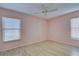 Simple bedroom with light pink walls, wood-look flooring, and two windows with blinds at 612 Deerwood Ave # 169, Englewood, FL 34223