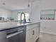 Modern kitchen island with stainless steel dishwasher, white cabinets and barstool seating at 19060 Moscato Ct, Venice, FL 34293
