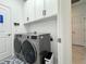 Functional laundry room features modern washer and dryer, white cabinetry, and ample space for efficient chores at 19060 Moscato Ct, Venice, FL 34293