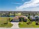 Aerial view of a one-story home that has a three-car garage, well manicured lawn, and water view at 849 Rotonda Cir, Rotonda West, FL 33947