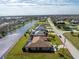 Aerial view of home with water view, manicured lawn, pool, and three-car garage at 849 Rotonda Cir, Rotonda West, FL 33947