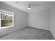Spacious bedroom with a window, gray carpet, and ceiling fan at 19196 Raymond Ave, Port Charlotte, FL 33954