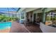 Covered back patio with brick pavers, dining set, and sliding glass doors leading to living space at 15048 Spanish Point Dr, Port Charlotte, FL 33981